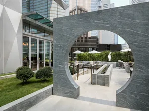 An outdoor patio made of granite with modern seating arrangements and greenery.