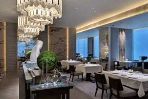 A modern restaurant interior with marble, glass, and stainless steel finishes.