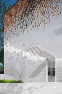 Modern minimalist building with white concrete exterior featuring a wooden shingle pattern.