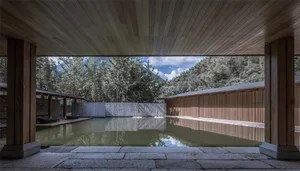 Swimming pool area with wooden and stone finishes in a minimalist hotel resort design.