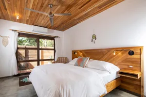Modern bedroom featuring a bed with white bedding, a wooden headboard, and a wooden ceiling.