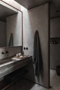 Modern bathroom with concrete walls, a floating vanity, and a wall-mounted faucet. Features minimalist design with a large mi