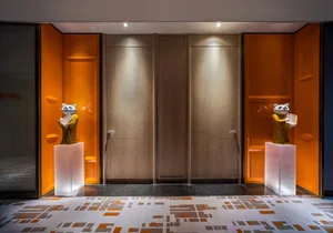 Modern entryway featuring wooden doors with concrete accents and panda statues.
