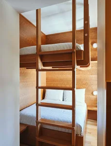 A modern industrial bunk bed made of wood with striped bedding in a bedroom setting.