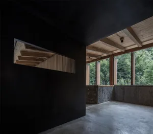 A minimalist modern interior space with concrete walls and floor, featuring a ceiling with wooden beams and large windows ove