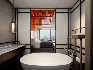 A modern minimalist bedroom featuring a circular bathtub, white walls, and a view of the city through large windows.