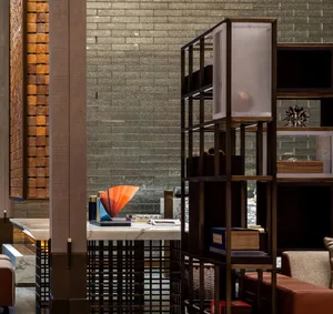 A modern lobby interior with metallic accents and glass elements, featuring a contemporary art piece and shelving unit.