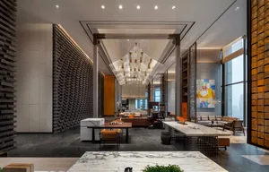 A spacious, modern lobby features a grand marble reception desk, metal chandelier, and contemporary seating.
