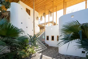 Modern residential courtyard with concrete steps, wood beams, and greenery.