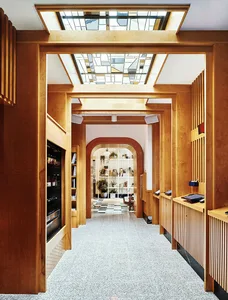 A modern retail shop interior with wooden walls and floors, featuring a glass ceiling with colorful geometric patterns.
