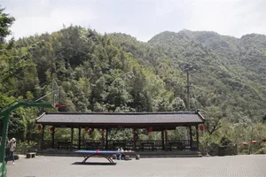 Outdoor pavilion with mountains in the background, featuring stone and wooden structures.