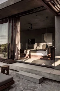 A minimalist bedroom featuring a concrete floor, bed, and wall art.