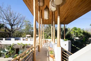 A minimalist residential balcony featuring wooden structures, concrete flooring, and abundant natural light.