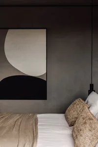 A minimalist bedroom featuring neutral-toned textiles on the bed.