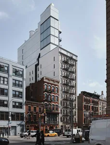 A modern glass building with a unique geometric design and industrial elements in the surrounding area.