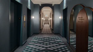 A modern hotel hallway featuring a patterned carpet and wooden accents.