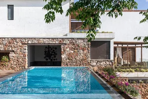 Modern house exterior featuring a pool with concrete walls and a green tree nearby.
