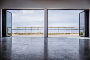 Modern interior space with concrete flooring and large windows overlooking a lake.