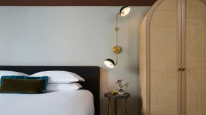 A modern minimalist bedroom with a white bed and teal accents.