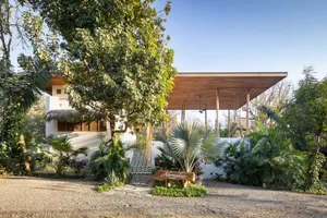 A modern residential exterior featuring concrete, stucco, and glass materials.