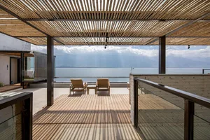 A modern residential patio featuring wood flooring and furniture.
