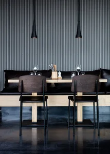 A modern restaurant interior featuring wooden tables and black leather seating.