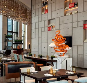 A modern restaurant with metal and leather seating, marble countertops, and a glass art installation.