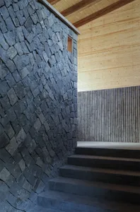 Modern interior design featuring stone walls, wooden paneling, and concrete stairs