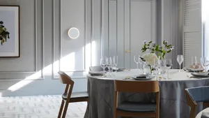 A minimalist dining room featuring glass tableware, wooden chairs, and fabric curtains.