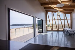 A minimalist space featuring glass walls and concrete flooring overlooking a scenic landscape.