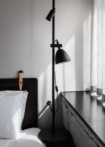 A minimalist bedroom featuring a concrete headboard and a black floor lamp.
