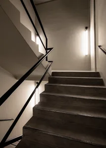 Modern concrete staircase with black metal railing in an interior setting.