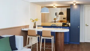 Modern kitchen with blue wood and marble bar, featuring sleek bar stools and white seating area with green and blue accents.