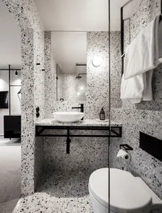 Modern residential bathroom with white and black terrazzo tiles, white sink, and black fixtures.