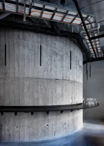 A sleek, modern concrete bar with black metal railings and industrial lighting fixtures.