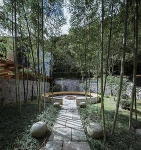 A serene bamboo garden patio featuring a stone pathway and seating area.