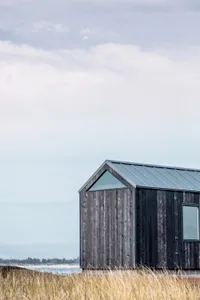 A minimalist vacation home with a weathered wood exterior and a modern metal roof.