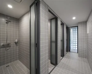 Modern bathroom with gray tiles and frosted glass doors.