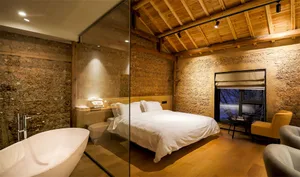 Modern bedroom with wooden floor, walls, and ceiling, featuring a large bed and a white bathtub.