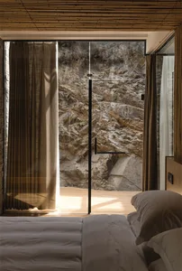 A minimalist bedroom with wood flooring and stone walls