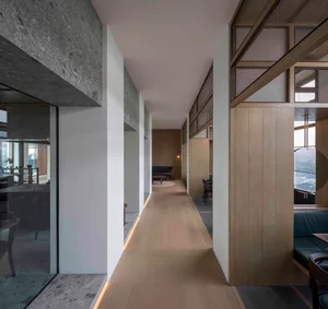 An image of a modern corridor with concrete, wood, and glass materials.