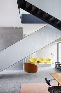 A modern living room featuring a yellow sofa, concrete wall, and metal primer accent wall.