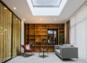 A modern living room featuring wooden shelves, glass windows, and a textile sofa.