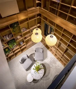 A modern living room with wooden shelves, grey furniture, and hanging lights.