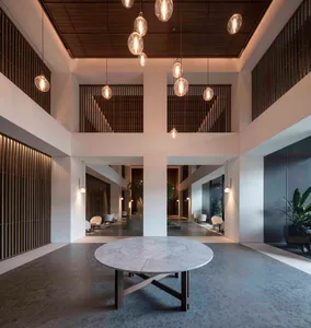 Modern, minimalist lobby interior with a round, white marble table and concrete flooring.
