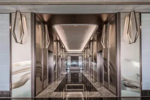 An elegant modern lobby featuring sleek, mirror-polished metal walls and a reflective floor.