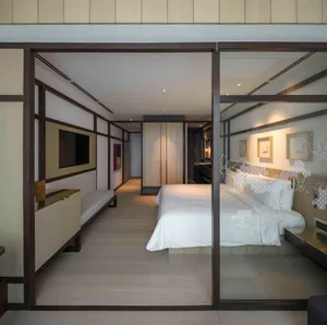 Modern minimalist bedroom suite featuring a king-sized bed with white bedding, stylish decor, and sleek furniture.