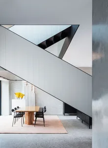 A modern minimalist dining room with a geometric design featuring a contemporary wooden dining table, black chairs, and a tex