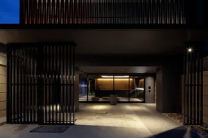 A modern, geometric entrance featuring metal gates and concrete flooring at dusk.