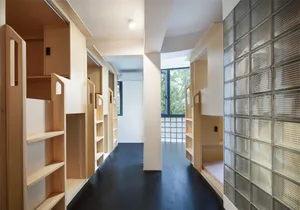 A hallway in an industrial-style apartment featuring wooden shelves and glass block walls.